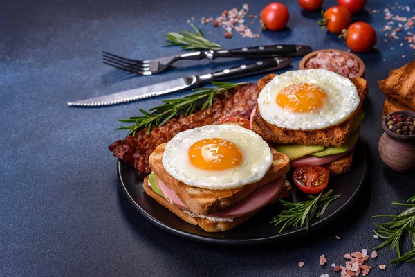 Fresh, delicious sandwiches with fried egg, ham, butter, avocado and sesame seeds on a wooden cutting board. Delicious healthy food