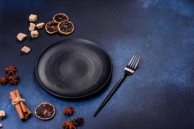 A piece of fresh delicious cake with nuts and chocolate on a black plate against a dark blue background. Desserts and sweets to the dinner table