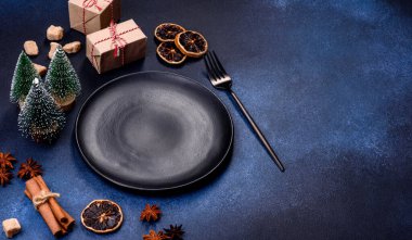 A piece of fresh delicious cake with nuts and chocolate on a black plate against a dark blue background. Desserts and sweets to the dinner table