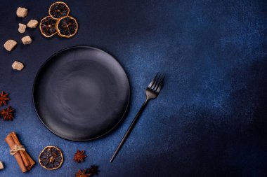 A piece of fresh delicious cake with nuts and chocolate on a black plate against a dark blue background. Desserts and sweets to the dinner table