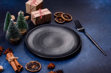 A piece of fresh delicious cake with nuts and chocolate on a black plate against a dark blue background. Desserts and sweets to the dinner table