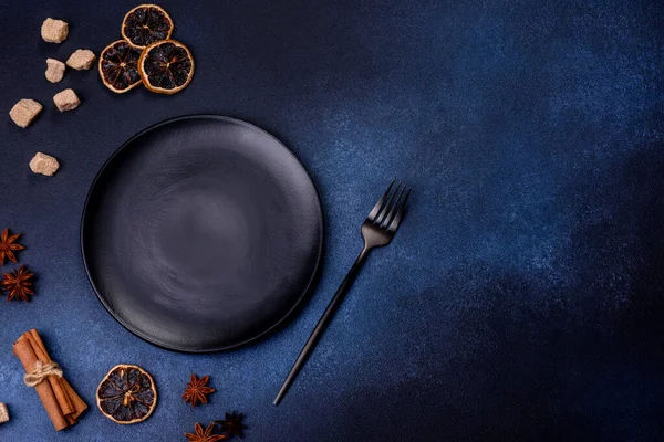 A piece of fresh delicious cake with nuts and chocolate on a black plate against a dark blue background. Desserts and sweets to the dinner table