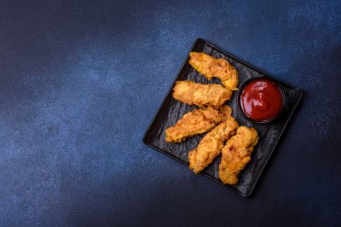 Chicken nuggets with tomato sauce on a concrete background. Copy space