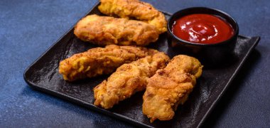 Chicken nuggets with tomato sauce on a concrete background. Copy space
