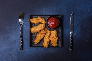 Chicken nuggets with tomato sauce on a concrete background. Copy space