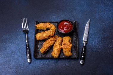 Chicken nuggets with tomato sauce on a concrete background. Copy space