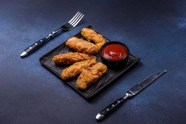 Chicken nuggets with tomato sauce on a concrete background. Copy space