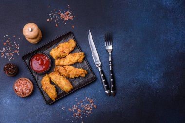 Chicken nuggets with tomato sauce on a concrete background. Copy space