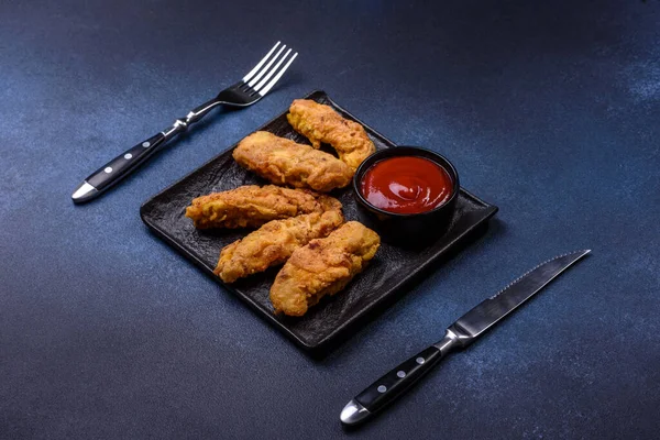 Chicken nuggets with tomato sauce on a concrete background. Copy space