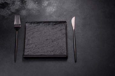 Empty square black plate over dark slate. Aerial view, with copy space