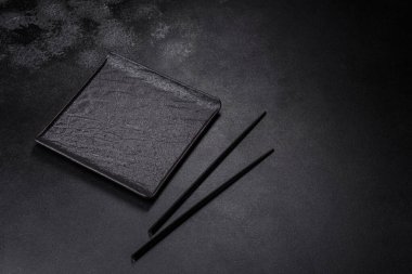 Empty square black plate over dark slate. Aerial view, with copy space
