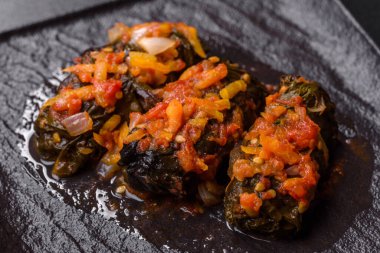 Dolma, stuffed grape leaves with rice and meat on a dark background. Caucasian and Turkish cuisine