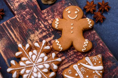 Elements of Christmas decorations, sweets and gingerbread on a wooden cutting board against a dark concrete background. Preparing for the holiday
