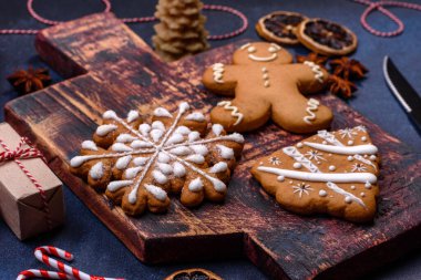 Elements of Christmas decorations, sweets and gingerbread on a wooden cutting board against a dark concrete background. Preparing for the holiday