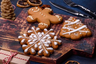 Elements of Christmas decorations, sweets and gingerbread on a wooden cutting board against a dark concrete background. Preparing for the holiday