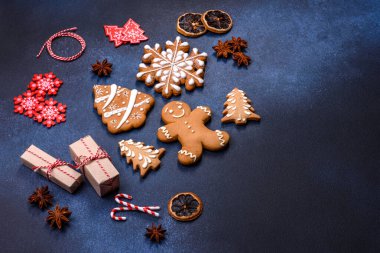Elements of Christmas decorations, sweets and gingerbread on a wooden cutting board against a dark concrete background. Preparing for the holiday