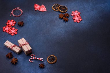 Elements of Christmas decorations, sweets and gingerbread on a wooden cutting board against a dark concrete background. Preparing for the holiday