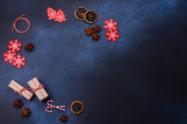 Elements of Christmas decorations, sweets and gingerbread on a wooden cutting board against a dark concrete background. Preparing for the holiday
