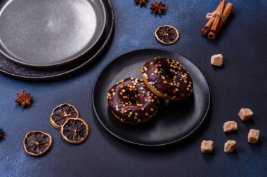 Pastries concept. Donuts with chocolate glaze with sprinkles, on a dark concrete table. Sweet food for a breakfast