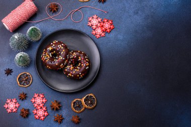 Pastries concept. Donuts with chocolate glaze with sprinkles, on a dark concrete table. Sweet food for a breakfast