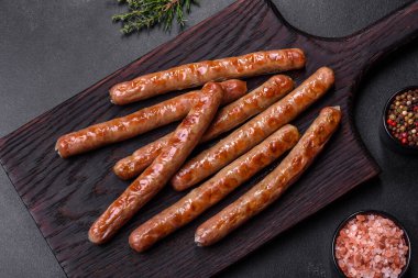 Grilled sausage with the addition of herbs and vegetables on the wooden cutting board. Grilling food, barbecue
