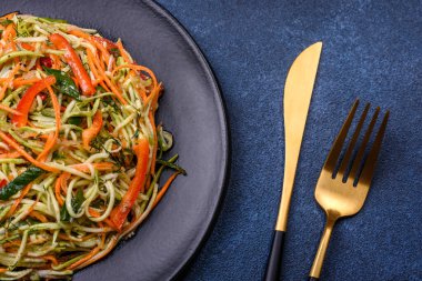 Beton zemin üzerinde ince dilimlenmiş havuç ve kabak salatası. Vejetaryen mutfağı