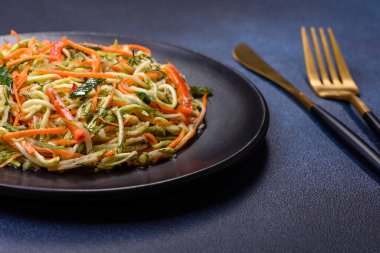 Beton zemin üzerinde ince dilimlenmiş havuç ve kabak salatası. Vejetaryen mutfağı