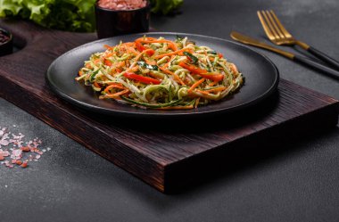 Beton zemin üzerinde ince dilimlenmiş havuç ve kabak salatası. Vejetaryen mutfağı