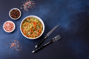 Beton zemin üzerinde ince dilimlenmiş havuç ve kabak salatası. Vejetaryen mutfağı