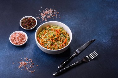 Beton zemin üzerinde ince dilimlenmiş havuç ve kabak salatası. Vejetaryen mutfağı