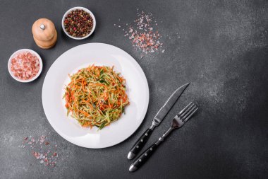 Beton zemin üzerinde ince dilimlenmiş havuç ve kabak salatası. Vejetaryen mutfağı