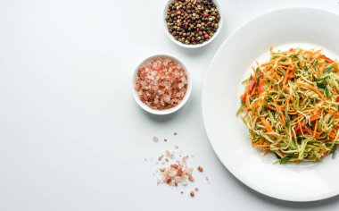 Beton zemin üzerinde ince dilimlenmiş havuç ve kabak salatası. Vejetaryen mutfağı