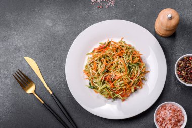 Beton zemin üzerinde ince dilimlenmiş havuç ve kabak salatası. Vejetaryen mutfağı