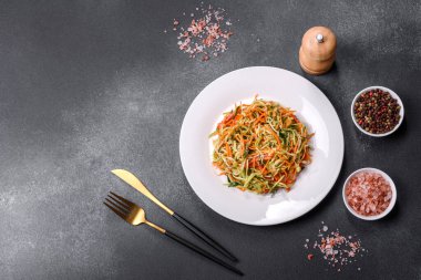 Beton zemin üzerinde ince dilimlenmiş havuç ve kabak salatası. Vejetaryen mutfağı