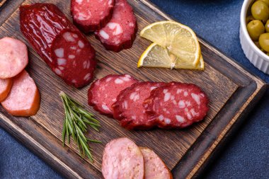 Lezzetli taze füme sosisler tahta kesme tahtasıyla kesilmiş koyu beton bir arka planda.