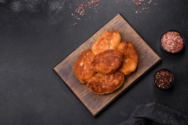 Cooking pies with potato on a wooden cutting board on a black background