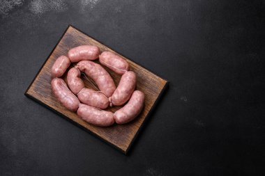 Ahşap kesim tahtasındaki çiğ ızgara sosis, baharatlar ve sebzelerle. Metnin için boş yer