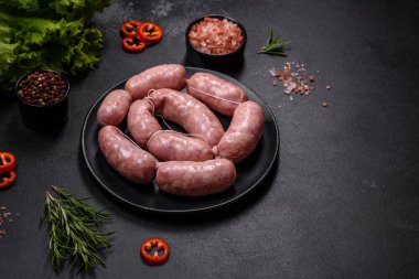 Ahşap kesim tahtasındaki çiğ ızgara sosis, baharatlar ve sebzelerle. Metnin için boş yer