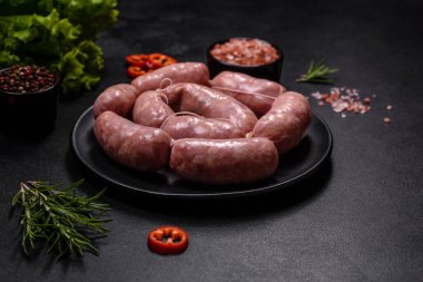 Ahşap kesim tahtasındaki çiğ ızgara sosis, baharatlar ve sebzelerle. Metnin için boş yer