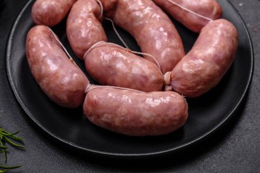 Ahşap kesim tahtasındaki çiğ ızgara sosis, baharatlar ve sebzelerle. Metnin için boş yer