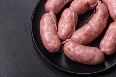 Ahşap kesim tahtasındaki çiğ ızgara sosis, baharatlar ve sebzelerle. Metnin için boş yer