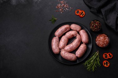 Ahşap kesim tahtasındaki çiğ ızgara sosis, baharatlar ve sebzelerle. Metnin için boş yer