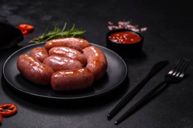 Siyah bir zemin üzerinde baharat ve bitkilerle ızgara sosisler ve fotokopi alanı.