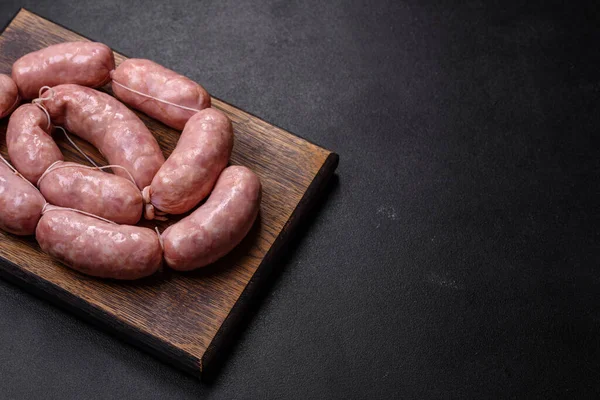 Ahşap kesim tahtasındaki çiğ ızgara sosis, baharatlar ve sebzelerle. Metnin için boş yer