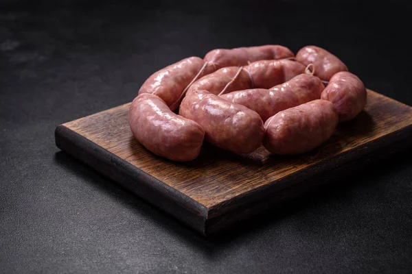 Ahşap kesim tahtasındaki çiğ ızgara sosis, baharatlar ve sebzelerle. Metnin için boş yer