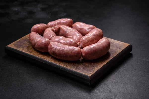 Ahşap kesim tahtasındaki çiğ ızgara sosis, baharatlar ve sebzelerle. Metnin için boş yer