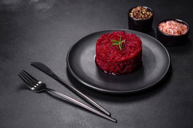 Kavrulmuş pancar kökü silindir şeklinde ve siyah bir tabakta koyu beton bir zemine karşı hazır.