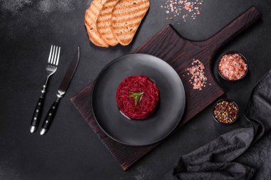 Kavrulmuş pancar kökü silindir şeklinde ve siyah bir tabakta koyu beton bir zemine karşı hazır.