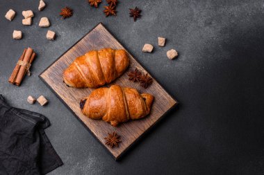 Tahta kesme tahtasında koyu beton arka planda taze çikolatalı kruvasanlar.