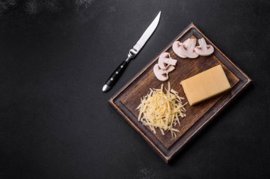 Çiğ makarna, mantar, soğan, kıyma, baharat ve otlar, domates soslu lezzetli bir macun yapmak için koyu beton arka planda.